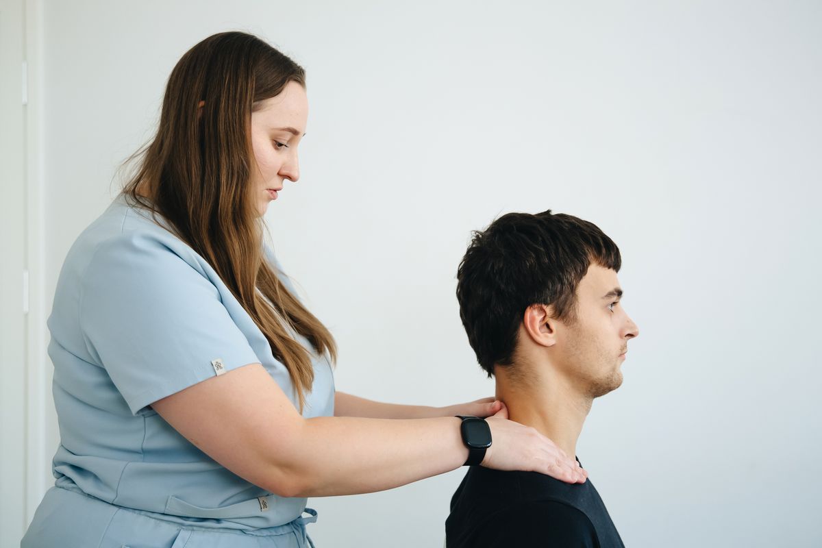 Fisioterapeuta acompanhando região cervical de paciente